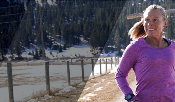 Woman wearing a purple shirt running with trees in background