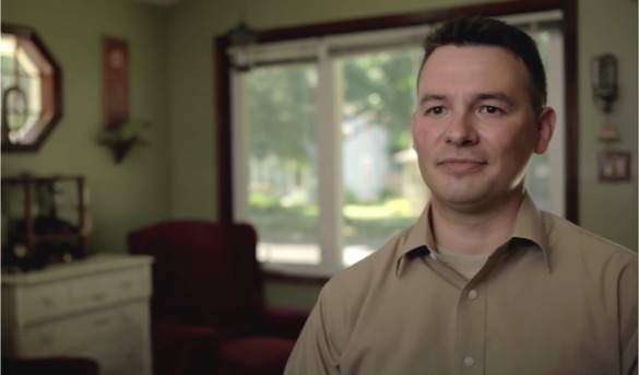 Man with tan shirt sitting in front of slider doors